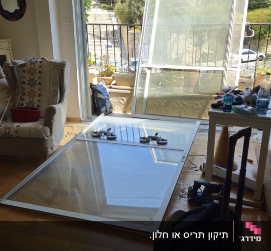 חלון זכוכית גדול מונח על הרצפה ליד מרפסת